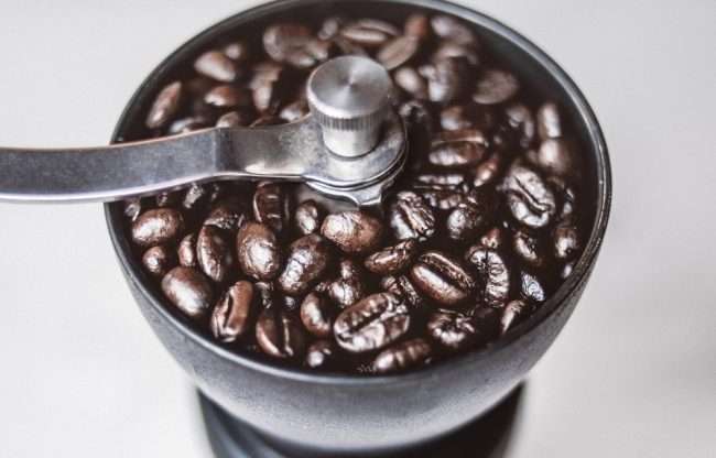 Na zdjęciu znajduje się dobry młynek do kawy wypełniony jej ziarnami.
